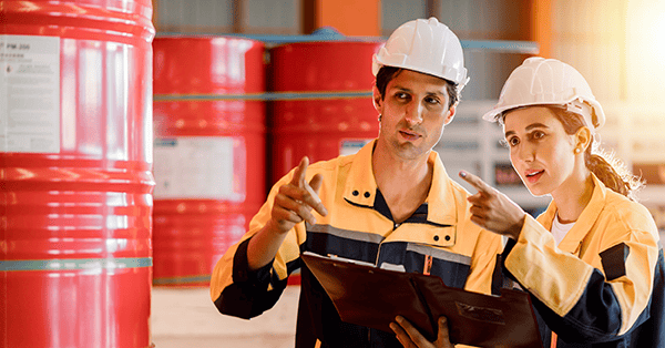 Arbeiter in Arbeitsschutzausrüstung gekleidet stehen auf einer Baustelle und beraten sich untereinander.