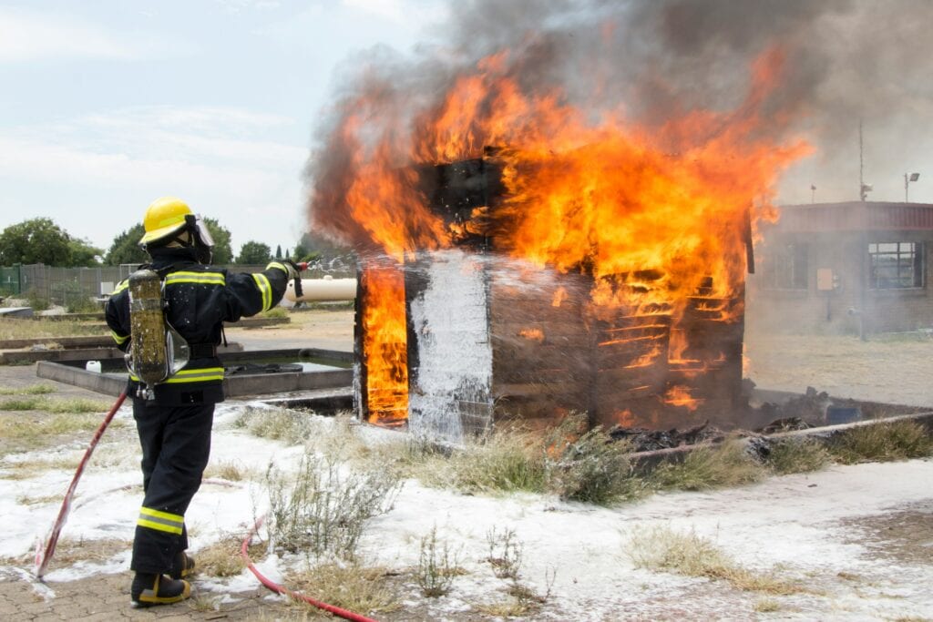 Die Feuerwehr löscht eine brennende Holzhütte auf einer Wiese