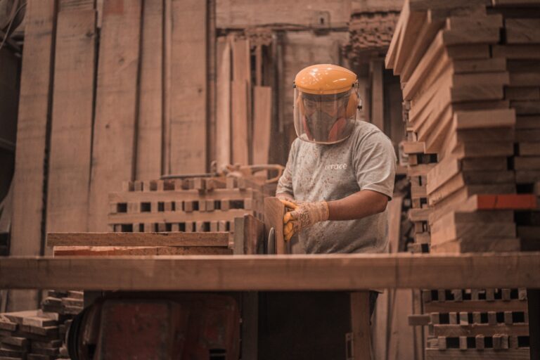Person trägt Schutzkleidung, während Holz arbeiten.
